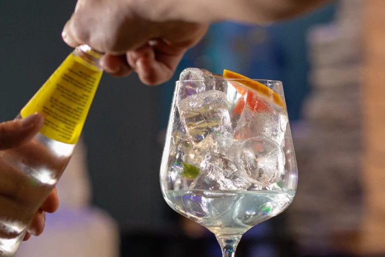 Preparación de cóctel con hielo y naranja en bar destino cuéllar café y copas.