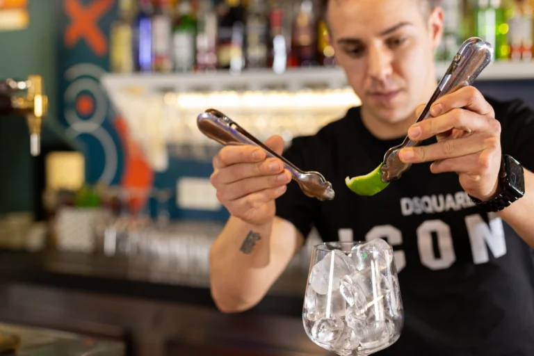 Barman preparando cóctel con lima en bar destino cuéllar café y copas.